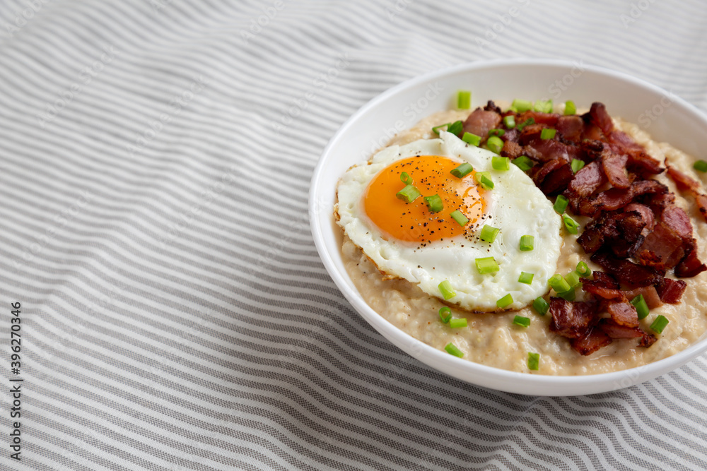 Homemade Cheesy Bacon Savory Oatmeal Bowl on cloth, low angle view. Copy space.