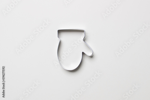 cookie cutter in form of glove on white colored paper background. isolated. close up. mock up