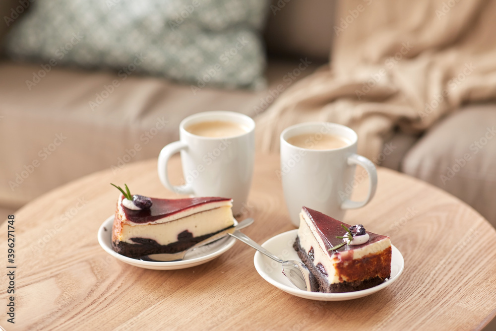 food, junk-food, culinary, baking and holidays concept - pieces of delicious cake on saucers with spoons and coffee cups on wooden table