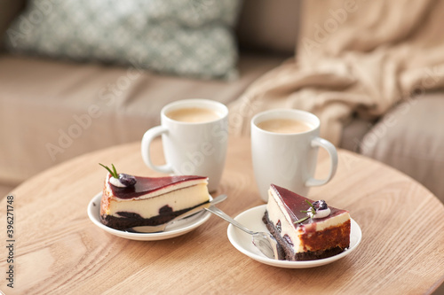 food, junk-food, culinary, baking and holidays concept - pieces of delicious cake on saucers with spoons and coffee cups on wooden table