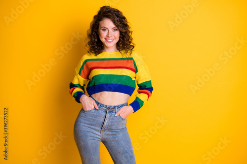 Photo portrait of confident girl with two hands in pockets isolated on bright yellow colored background