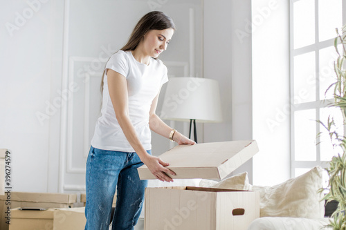 young woman opening a box in a new apartment