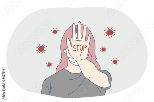 Danger or coronavirus infection epidemic, protective facial mask, pandemic concept. Young woman in medical mask standing and showing stop sign on palm with hand in corona bacteria flow outside 