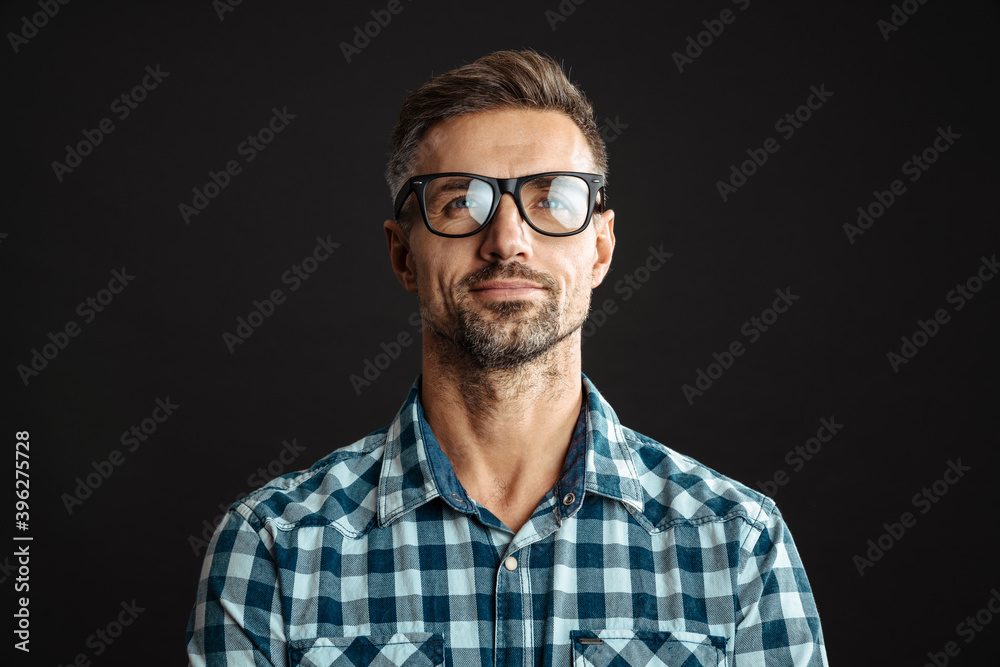 Handsome pleased man in eyeglasses posing and looking upward Handsome pleased man in eyeglasses posing and looking upward