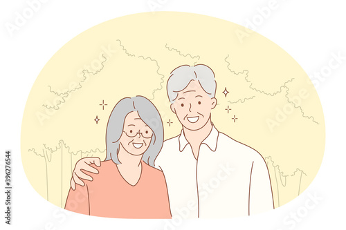 Senior elderly couple living happy active lifestyle concept. Portrait of happy mature aged couple pensioners woman and man standing hugging and looking at camera outdoors. Retiree, pensioner happiness