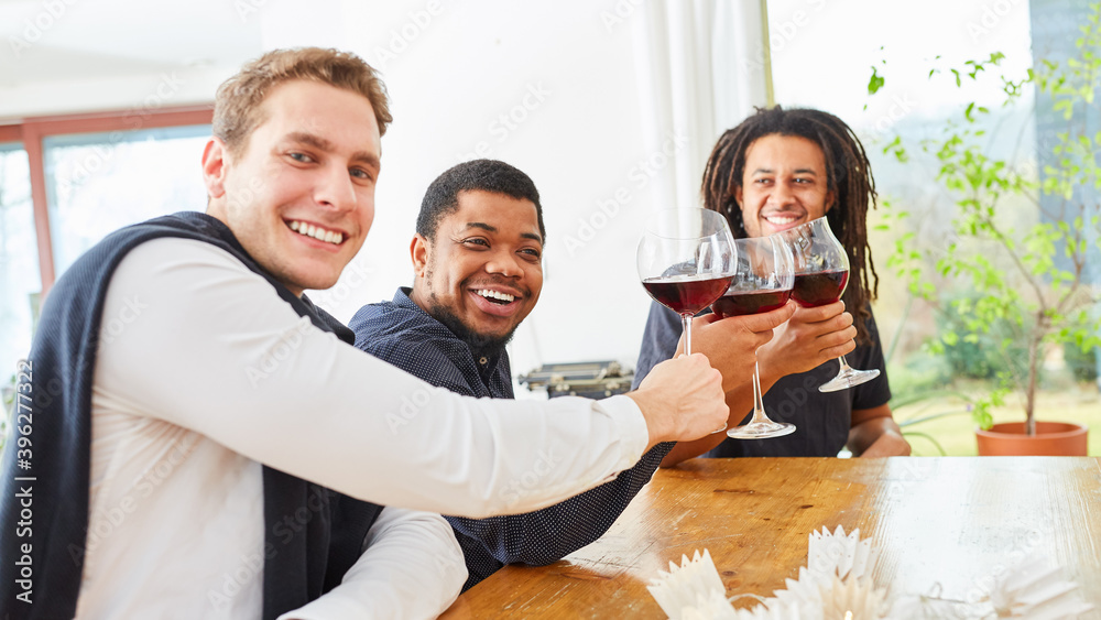 Obraz premium Men as friends toasting with a glass of red wine in a shared kitchen