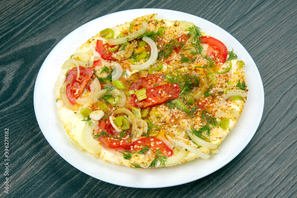 cooked fried omelet with herbs and vegetables in a white plate on a wooden table cooked fried omelet with herbs and vegetables in a white plate on a wooden table