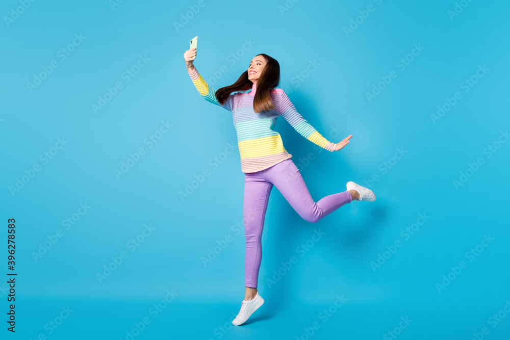 Full length body size view of attractive slim cheerful girl jumping taking making self selfie having fun isolated shine blue color background Full length body size view of attractive slim cheerful girl jumping taking making self selfie having fun isolated shine blue color background