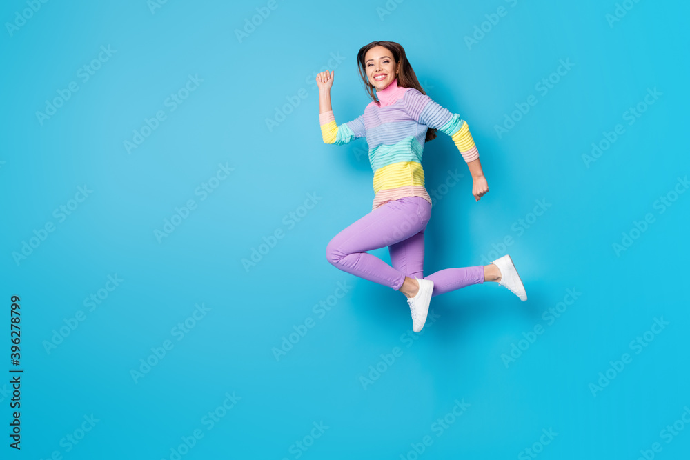 Full length body size view of attractive active purposeful cheerful girl jumping running isolated on bright blue color background Full length body size view of attractive active purposeful cheerful girl jumping running isolated on bright blue color background