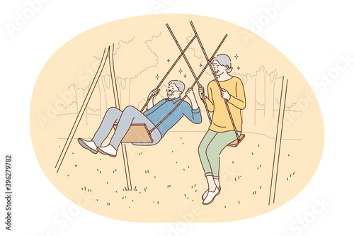 Senior elderly couple living happy active lifestyle concept. Happy mature loving couple pensioners woman and man riding on swing and having fun like children outdoors. Retiree, pensioner happiness