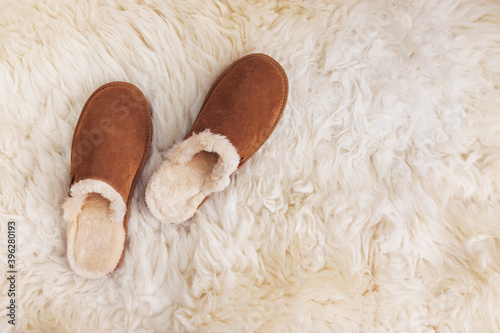 Cozy warm suede slippers on fur carpet photo