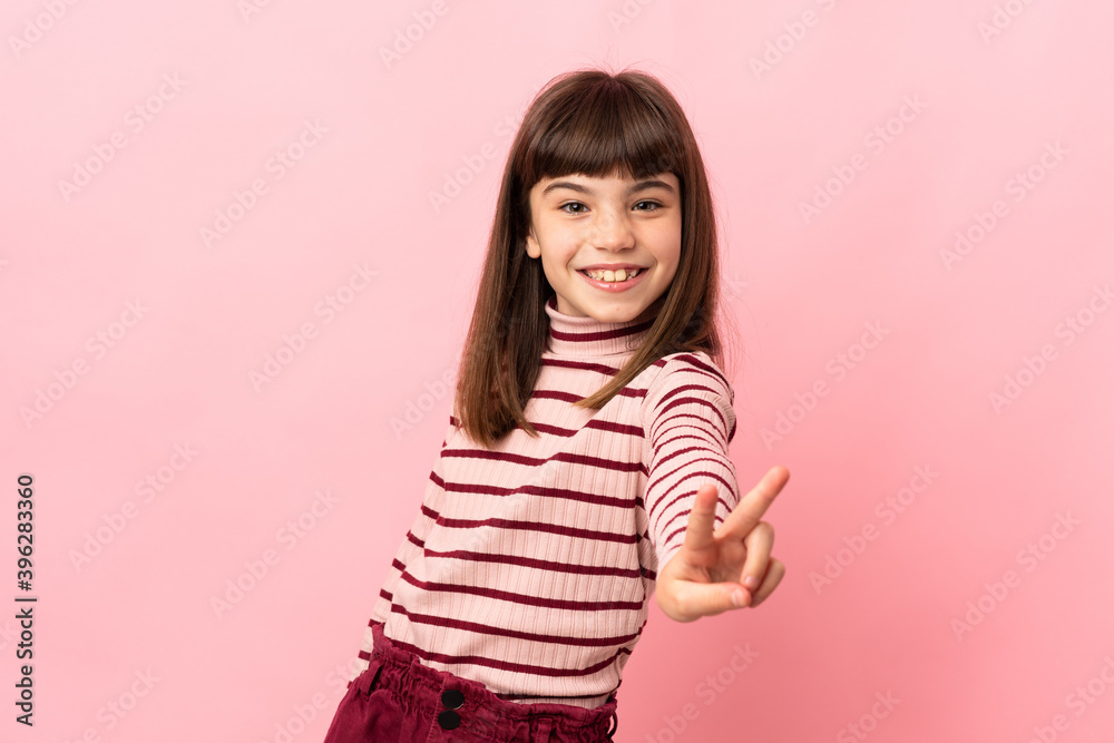 Little girl isolated on pink background smiling and showing victory sign Little girl isolated on pink background smiling and showing victory sign