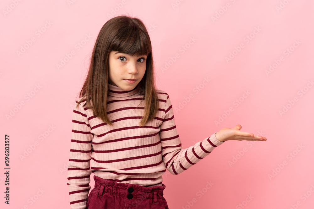 Little girl isolated on pink background making doubts gesture Little girl isolated on pink background making doubts gesture