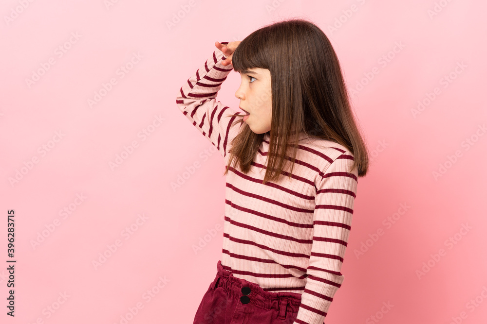 Little girl isolated on pink background with surprise expression while looking side Little girl isolated on pink background with surprise expression while looking side