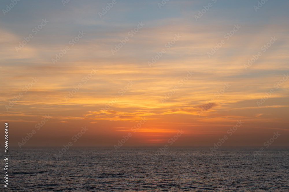 Orange and blue view of sunrise sky on the ocean.