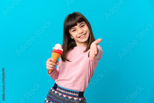Little girl with a cornet ice cream isolated on blue background shaking hands for closing a good deal