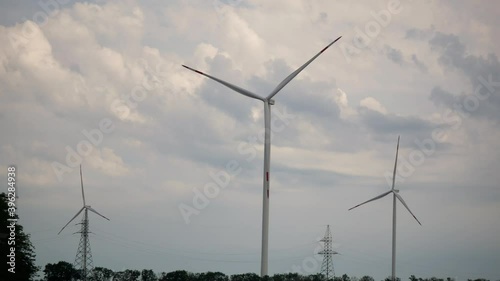 Alternative energy. Large wind power turbines generating clean renewable energy with blades in field with blue cloudy sky 