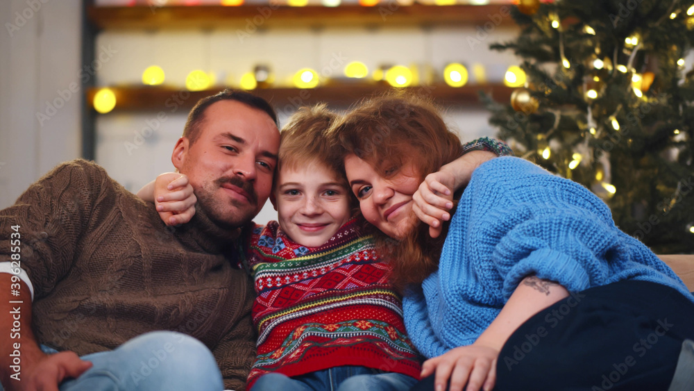 Fototapeta premium Cheerful family sitting together on couch at living room on christmas eve