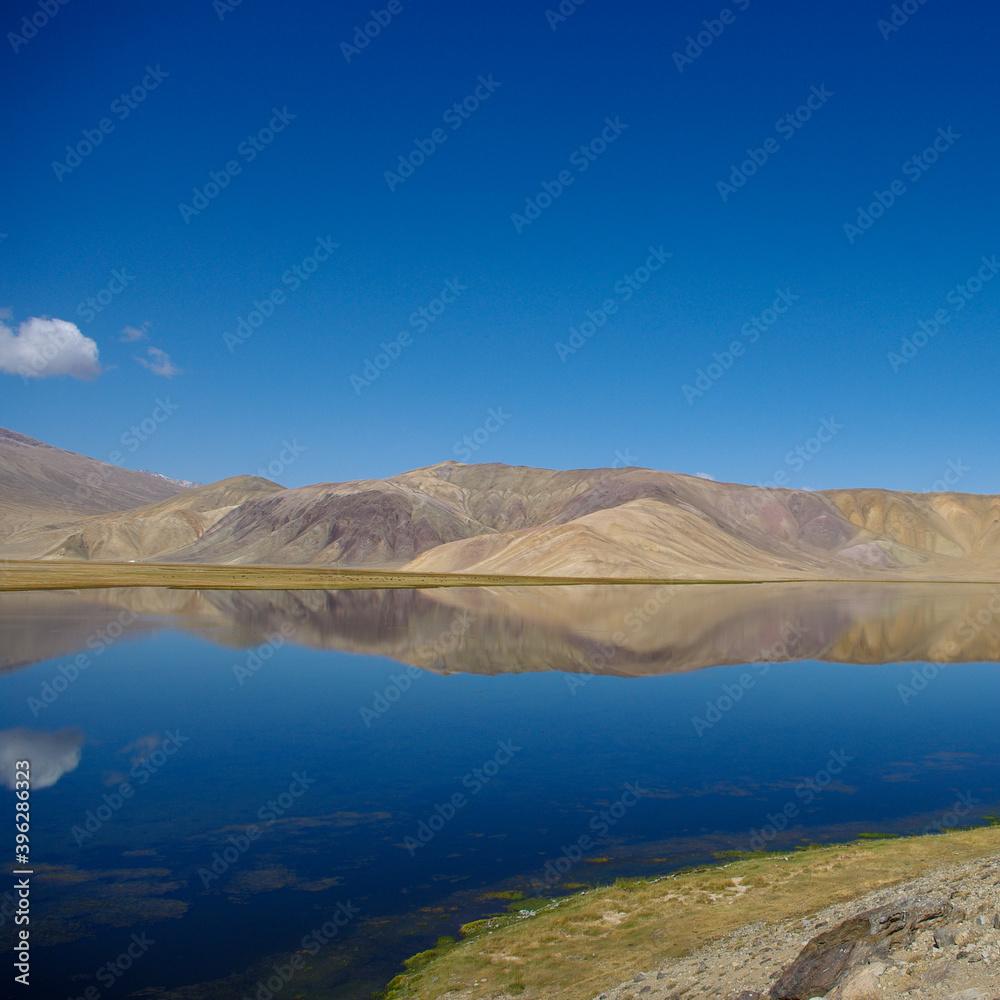 Spectacular view of pastel mountain reflection in high-altitude Bulunkul lake near the Pamir Highway in Gorno-Badakshan, Tajikistan