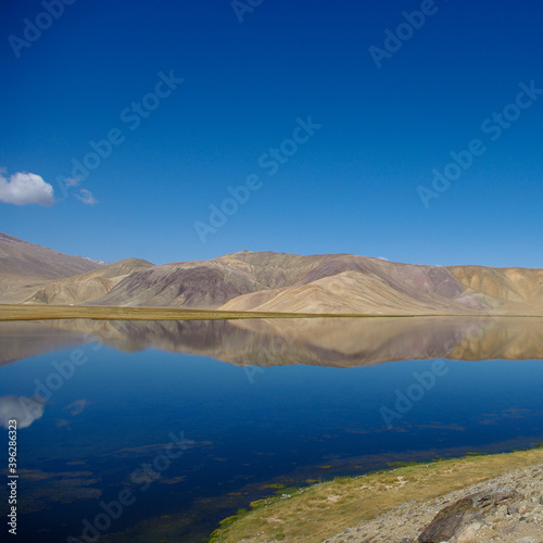 Spectacular view of pastel mountain reflection in high-altitude Bulunkul lake near the Pamir Highway in Gorno-Badakshan, Tajikistan