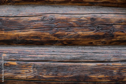 Wooden dark wall made of logs as background texture