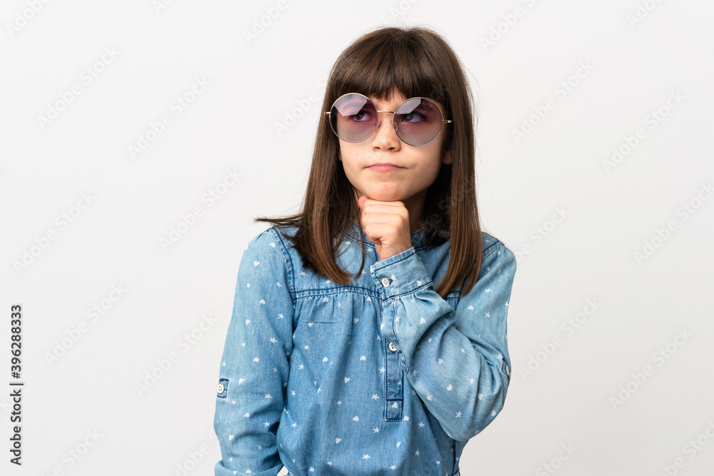 Little girl with sunglasses isolated on white background having doubts and thinking Little girl with sunglasses isolated on white background having doubts and thinking