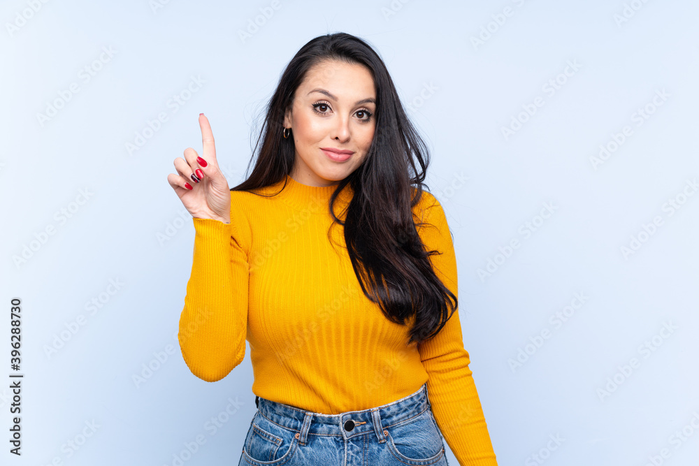 Young Colombian girl over isolated blue background pointing with the index finger a great idea Young Colombian girl over isolated blue background pointing with the index finger a great idea