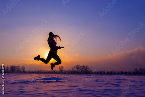 Girl on the bank of the winter sea at sunset. Woman splashes boiling water on cold air.
