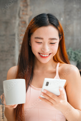Asian woman enjoy having coffee and watching something funny on social media.