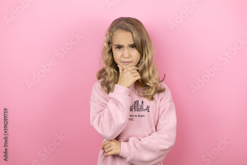 Young beautiful child girl standing over isolated pink background thinking