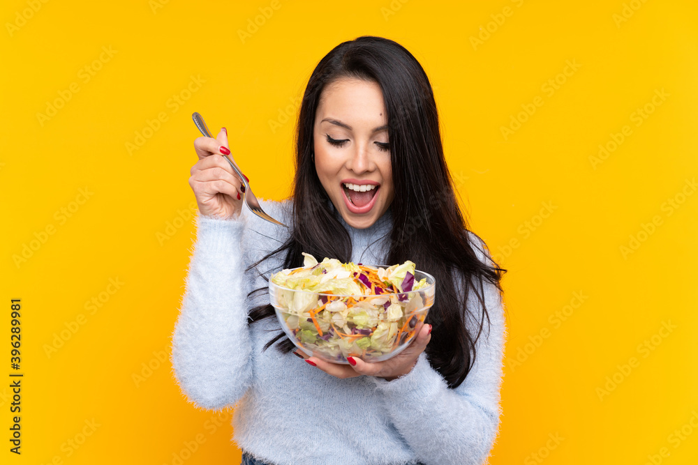 Young Colombian girl holding a salad over isolated background Young Colombian girl holding a salad over isolated background