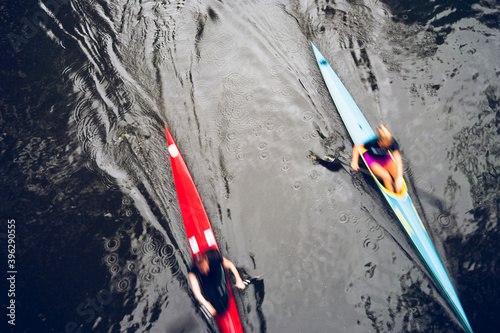 Two colored kayaks float at high speed in the water with the reflection of trees. Latvia, Baltic state