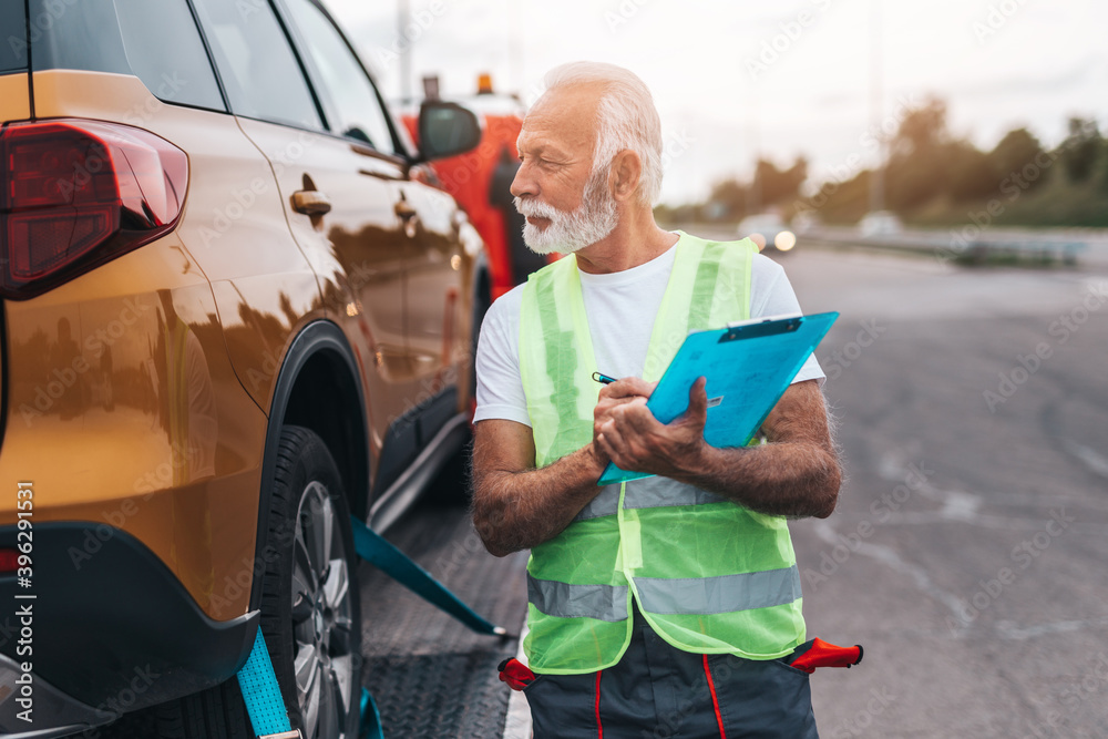 Handsome senior man working in towing service on the road. Roadside assistance concept. Handsome senior man working in towing service on the road. Roadside assistance concept.