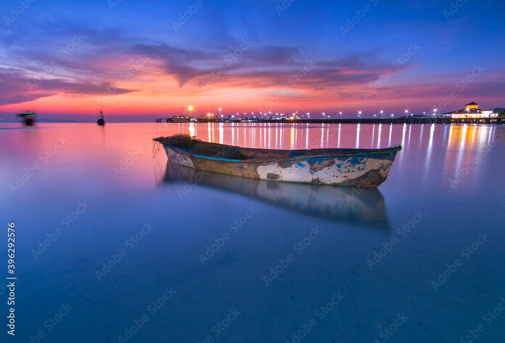 Fototapeta premium The little boat and the orange light reflected on the hull in the evening.