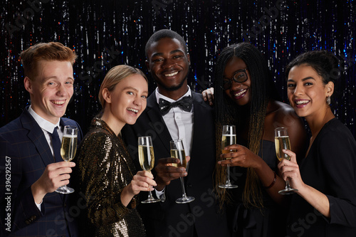 Canvas Print Waist up portrait of multi-ethnic group of friends holding champagne glasses and