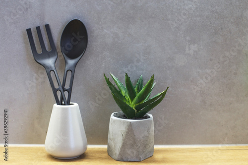 Different kitchen tools for cooking on the gray concrete wall. Kitchenware with plastic material