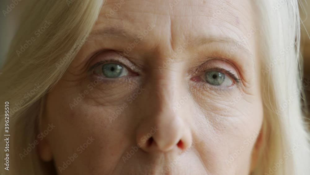 The face and eyes of the old woman. Large wrinkles on the old woman's face. Face close up