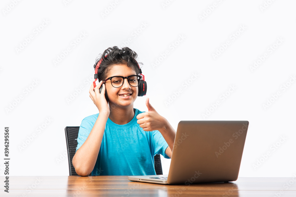 Indian asian kid studying or learning online using laptop computer ...