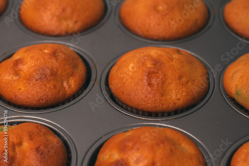 Freshly baked delicious sweet muffins with candied fruits in a baking dish. Homemade cake. Making cupcakes. Close-up