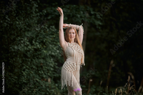 Portrait of a beautiful young graceful blonde woman dancing. In the woods in summer. Clothing of their eco-materials and macrame. The concept of natural products and harmony with nature.