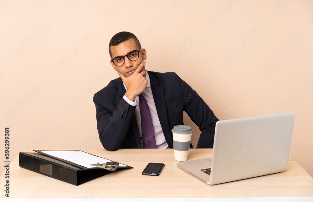 Young business man in his office with a laptop and other documents thinking Young business man in his office with a laptop and other documents thinking