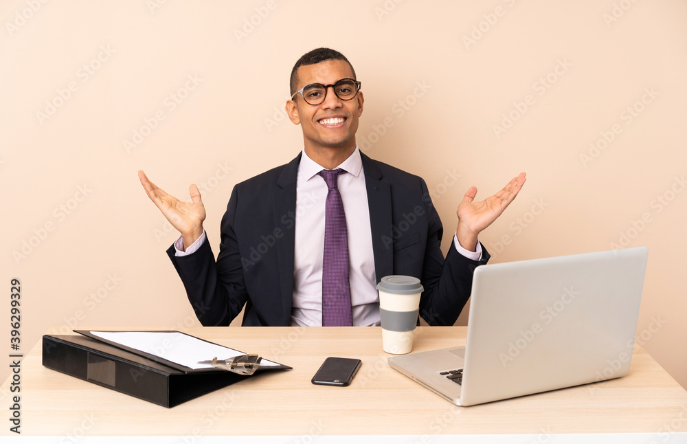 Young business man in his office with a laptop and other documents smiling a lot Young business man in his office with a laptop and other documents smiling a lot