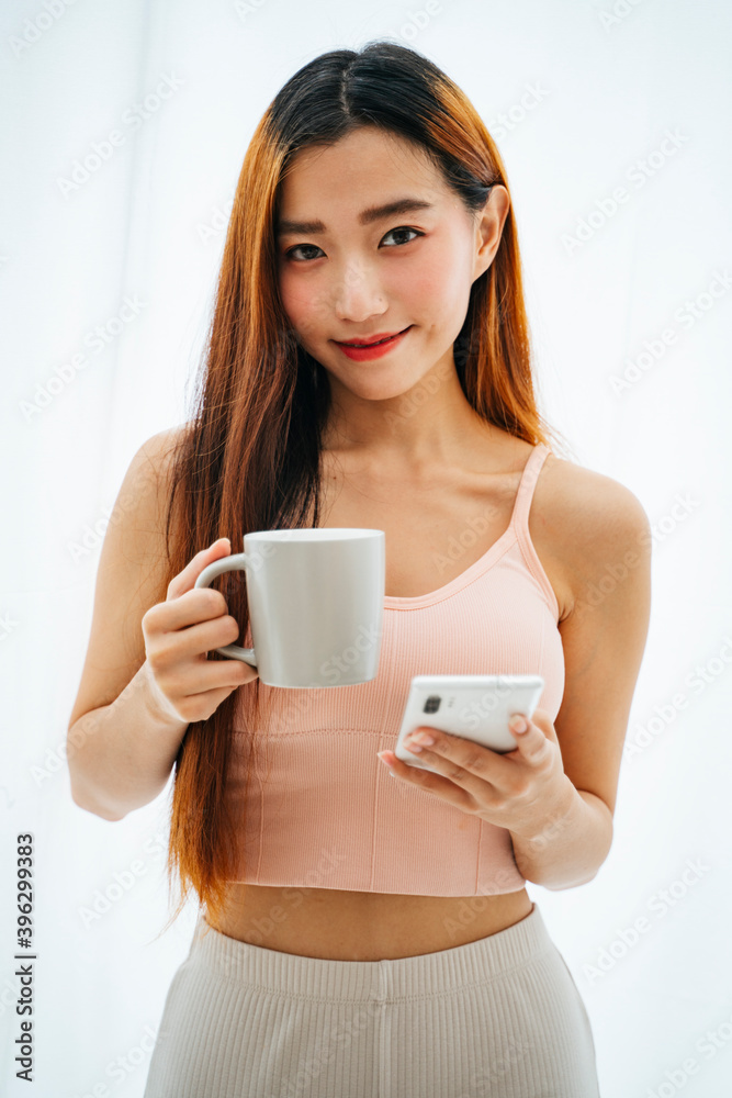 Beautiful young asian woman with a cup of coffee and smartphone.