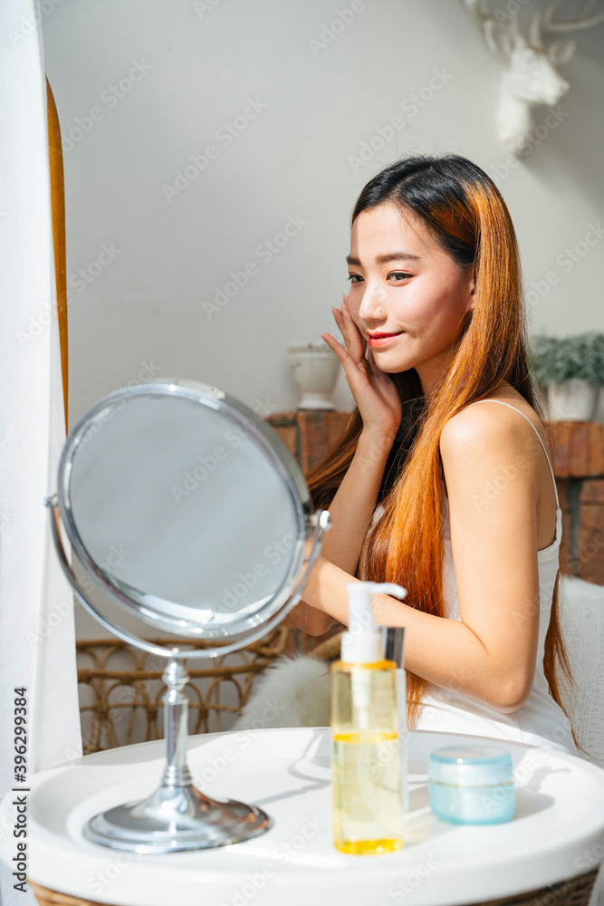 Beautiful asian woman using cosmetic for facial make up looking at mirror. Beautiful asian woman using cosmetic for facial make up looking at mirror.
