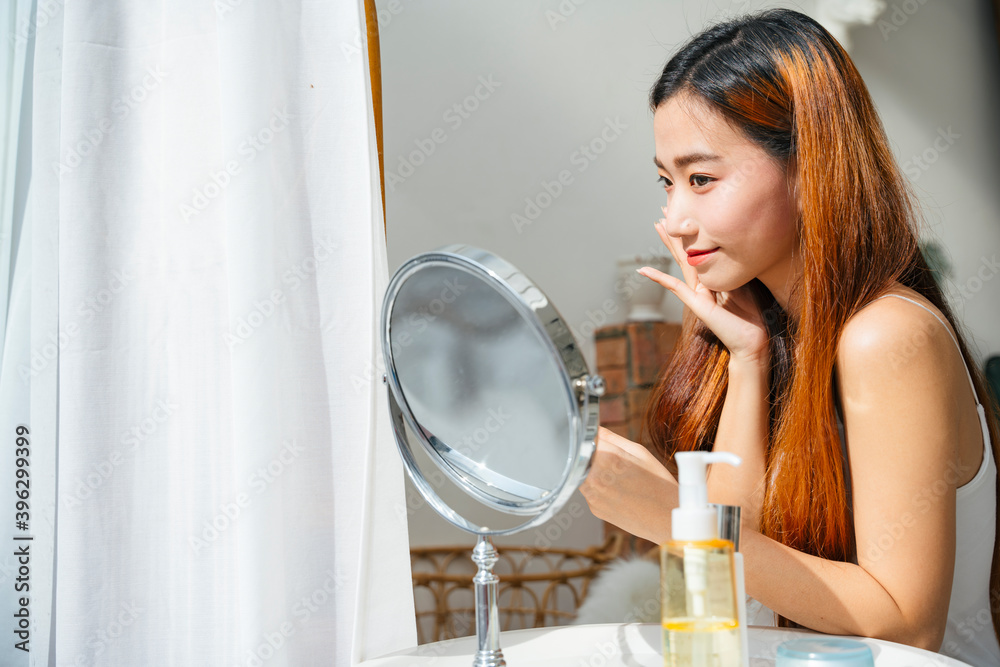 Beautiful asian woman using cosmetic for facial make up looking at mirror. Beautiful asian woman using cosmetic for facial make up looking at mirror.