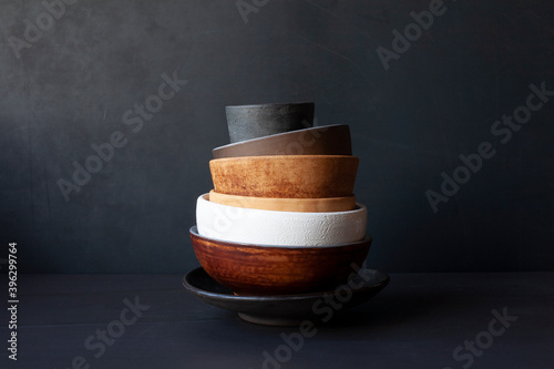 Still life with handmade ceramic dishware on a black background. Plates, bowls, pialas. Rustic style.