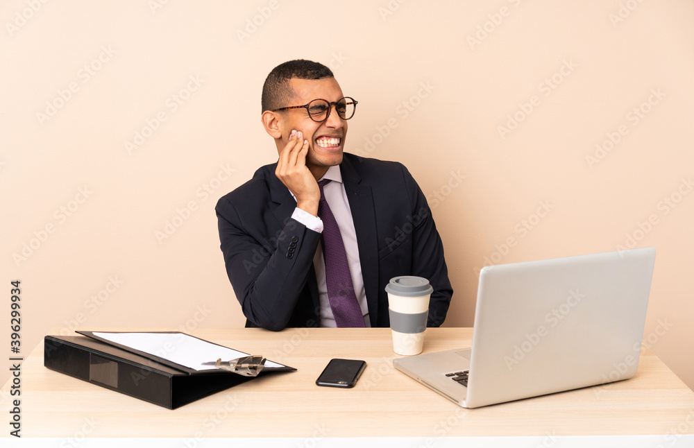 Young business man in his office with a laptop and other documents with toothache