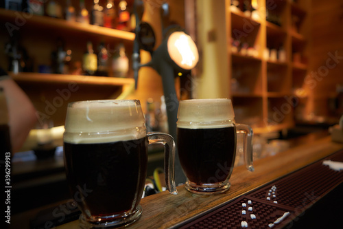 Foto The bartender pours a beer in a beer cups. Draught beer.