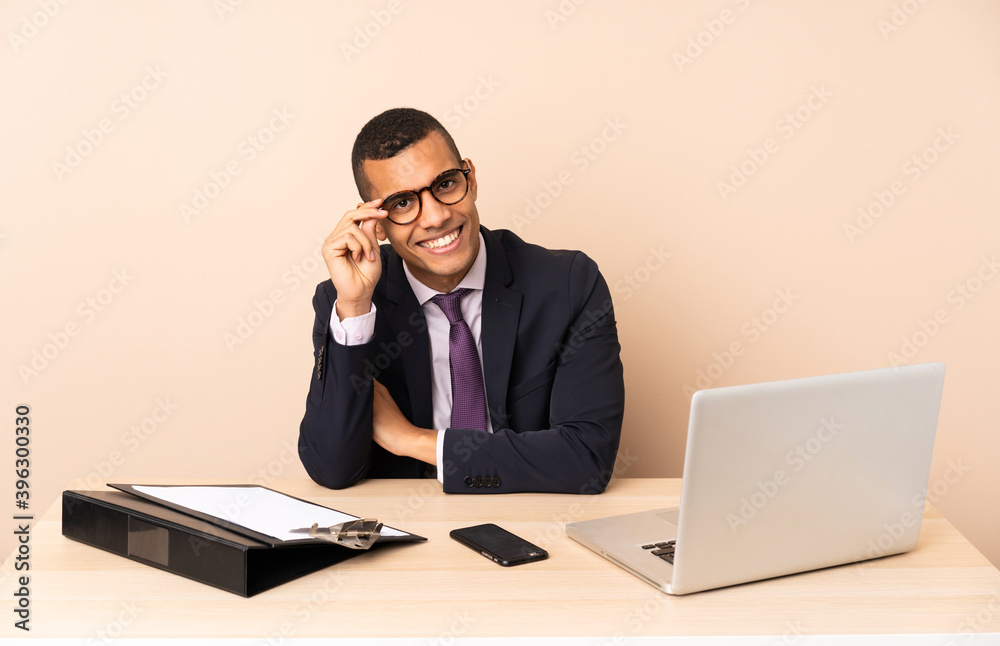 Young business man in his office with a laptop and other documents with glasses and happy Young business man in his office with a laptop and other documents with glasses and happy