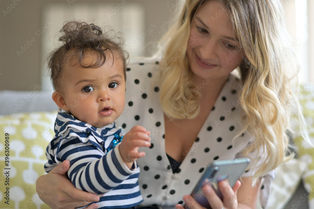 Young mom with baby girl playing with smartphone Young mom with baby girl playing with smartphone
